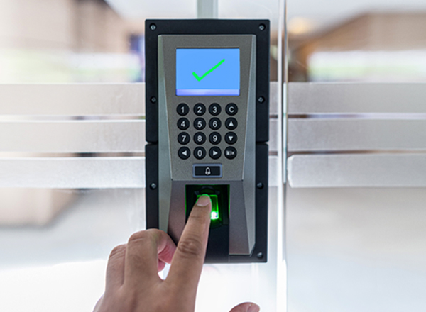 A person's hand using a security touchpad on glass door