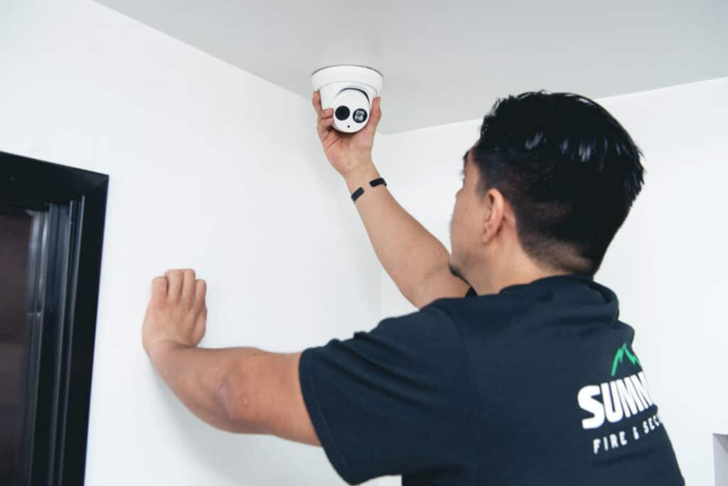 Summit Fire and Security employee installing a security camera