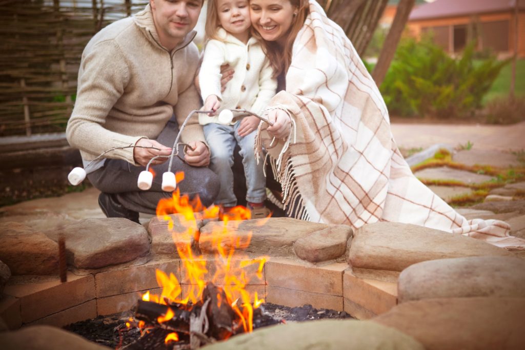 Family roasting marshmallows over the bonfire together.