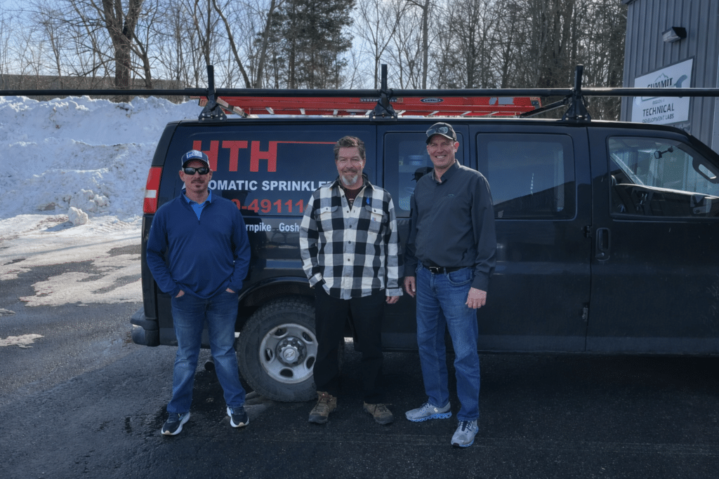 Three men in front of van.