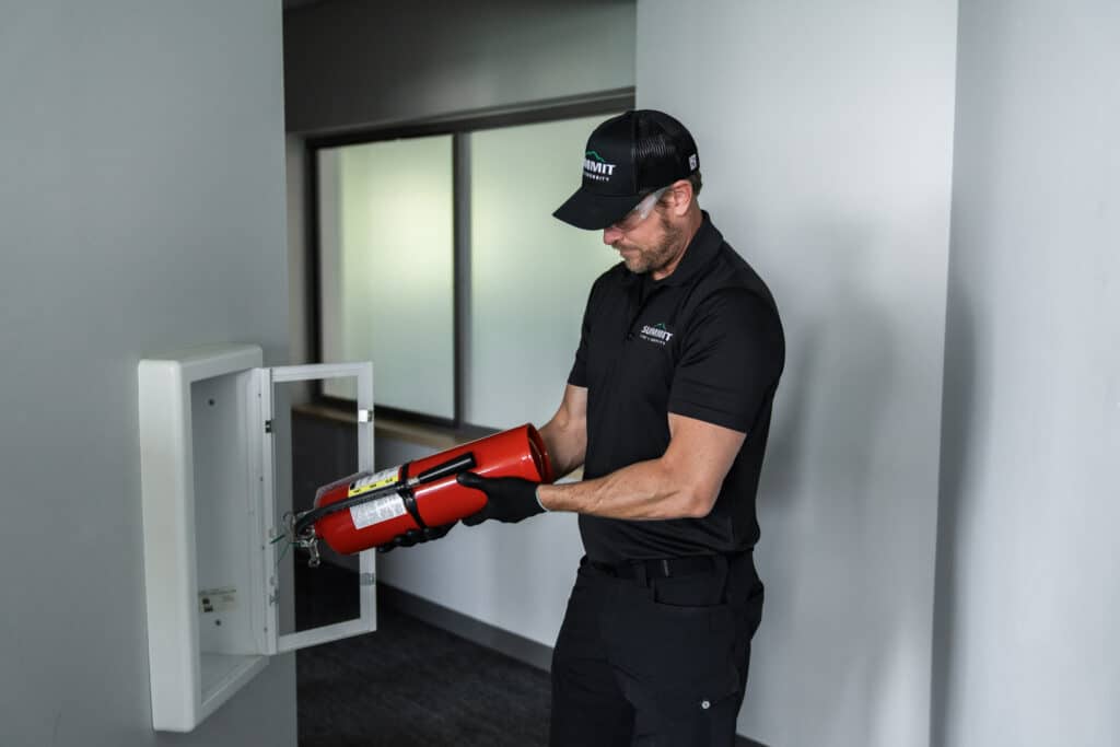 Summit Fire & Security technician observing a fire extinguisher